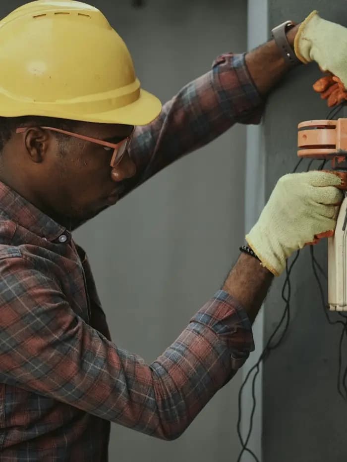 Técnico con casco conectando una caja de instalación en una fachada